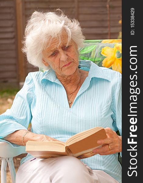 Mature woman relaxing with a book in her garden. Mature woman relaxing with a book in her garden