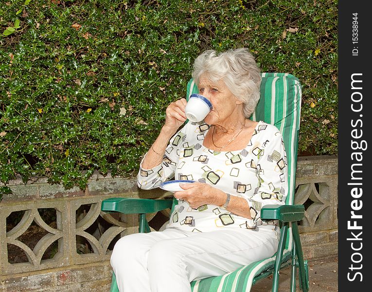 Senior lady enjoying a cup of tea in the garden. Senior lady enjoying a cup of tea in the garden