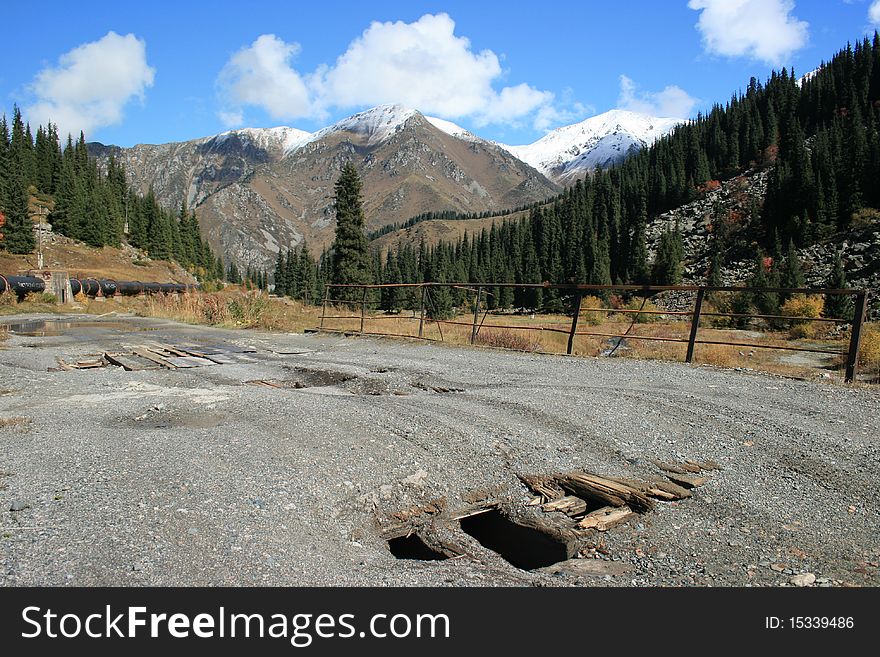 Broken bridge with tyre tracks on the road to Big Almaty Lake in Kazakhstan with mountains in the background. Broken bridge with tyre tracks on the road to Big Almaty Lake in Kazakhstan with mountains in the background