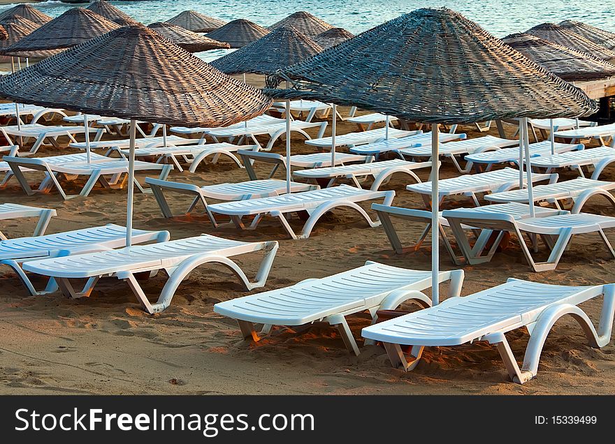 Rows of chaise longues under the beach umbrellas near the sea. Rows of chaise longues under the beach umbrellas near the sea