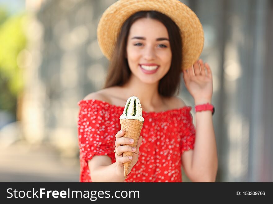 Happy young woman with delicious ice cream in waffle cone