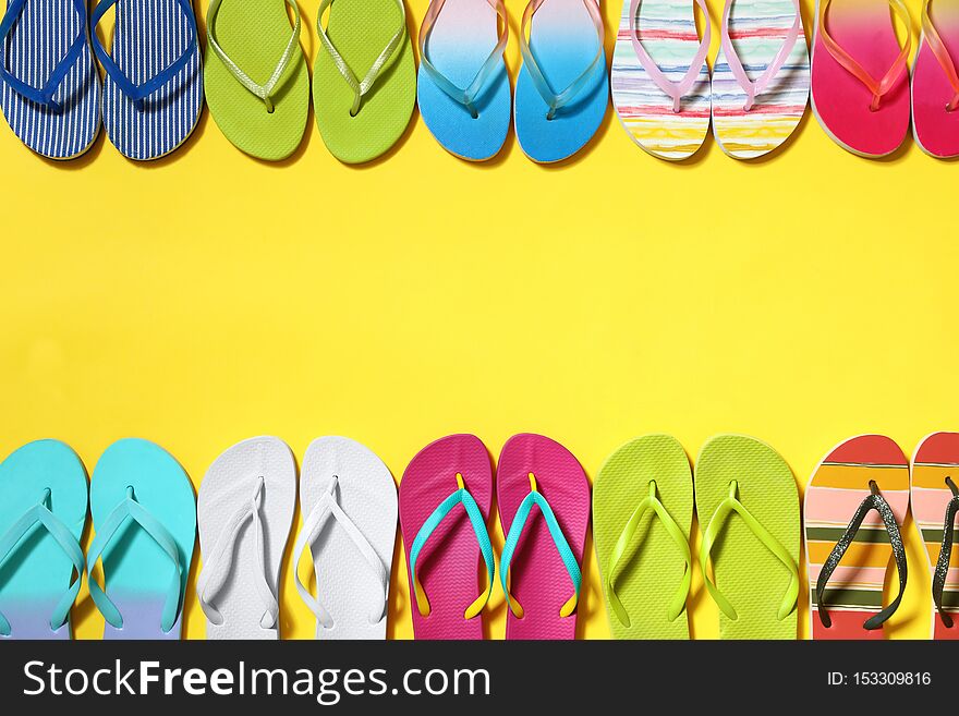 Different flip flops and space for text on yellow background, flat lay. Summer beach accessories