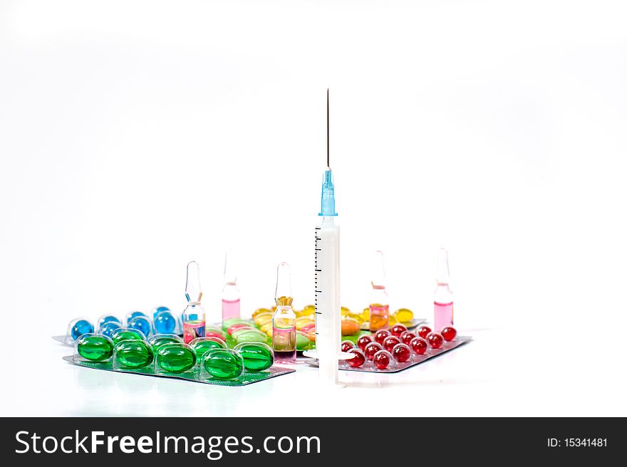 Various pills and syringe on white background