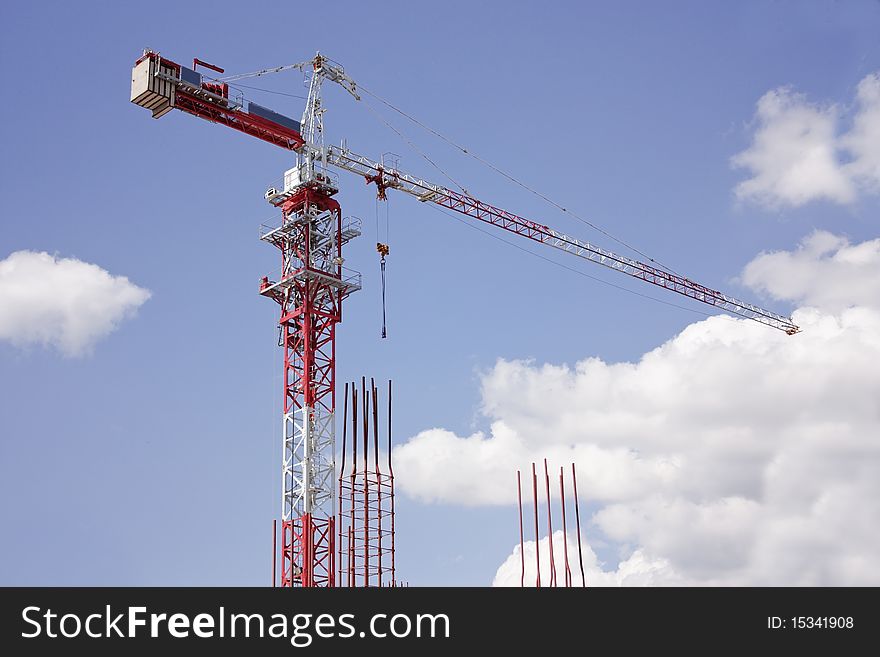 The upper part of the construction crane on a background of blue sky