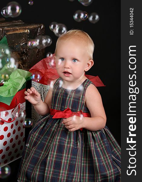 Cute blond toddler infront of an antique trunk with christmas presents. Cute blond toddler infront of an antique trunk with christmas presents