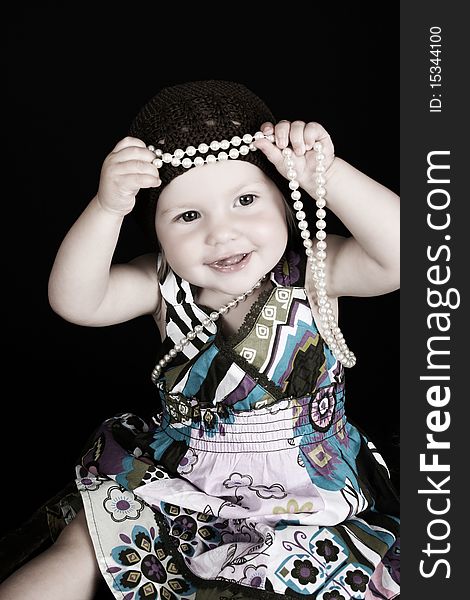 Beautiful little blond girl playing with a string of pearls