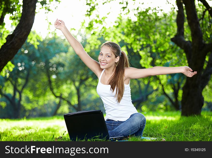 Girl with a laptop in the park with outstretched arms. Girl with a laptop in the park with outstretched arms