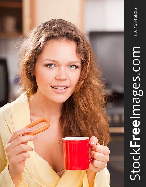 Attractive young adult with red cup of tea in the kitchen having a breakfast. Attractive young adult with red cup of tea in the kitchen having a breakfast