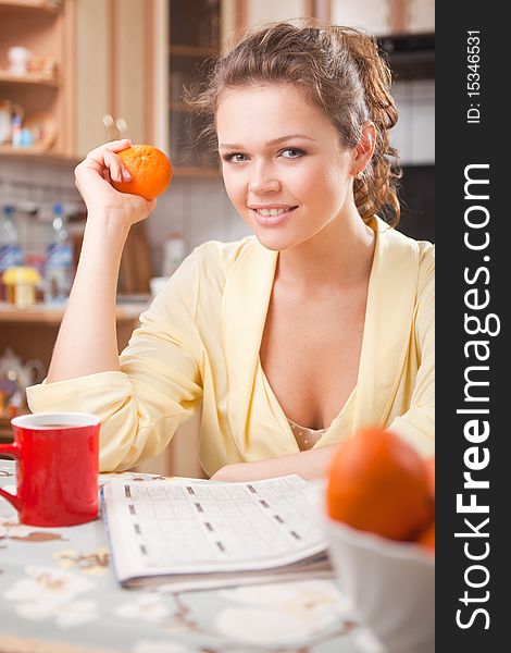 Pretty woman with in the kitchen with fresh orange and cup of tea having a breakfast. Pretty woman with in the kitchen with fresh orange and cup of tea having a breakfast