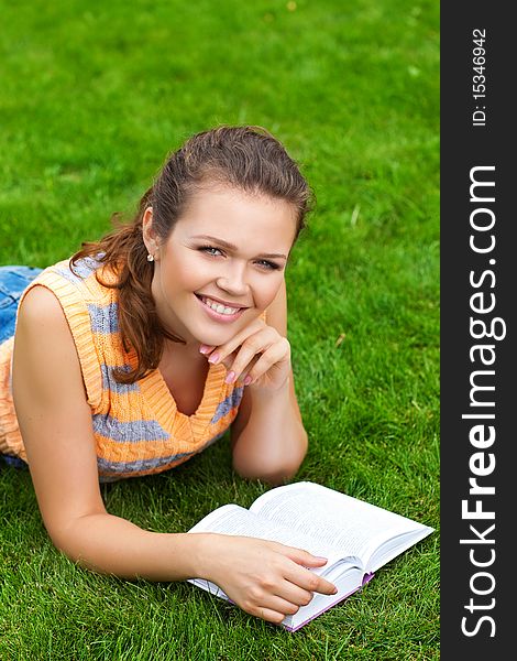 Beautiful young adult lying on grass with book. Beautiful young adult lying on grass with book