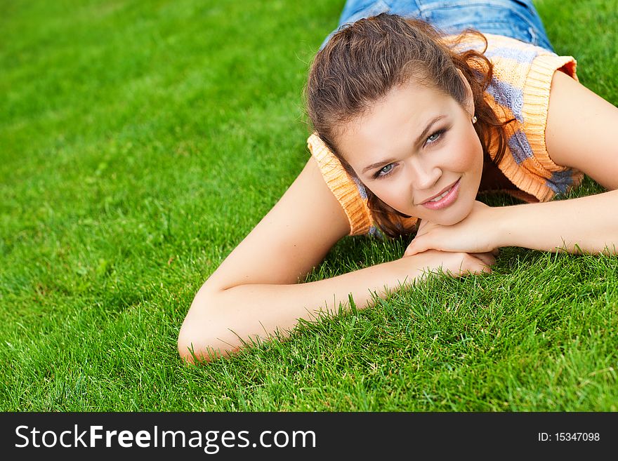 Pretty young caucasian woman lying on grass looking at camera. Pretty young caucasian woman lying on grass looking at camera
