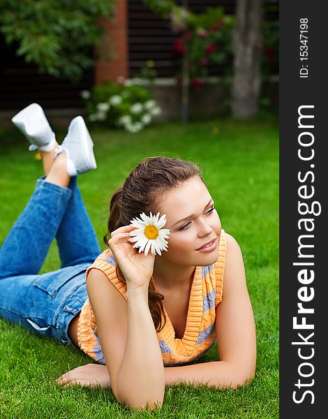 Attractive young teenager with flower lying on green grass. Attractive young teenager with flower lying on green grass