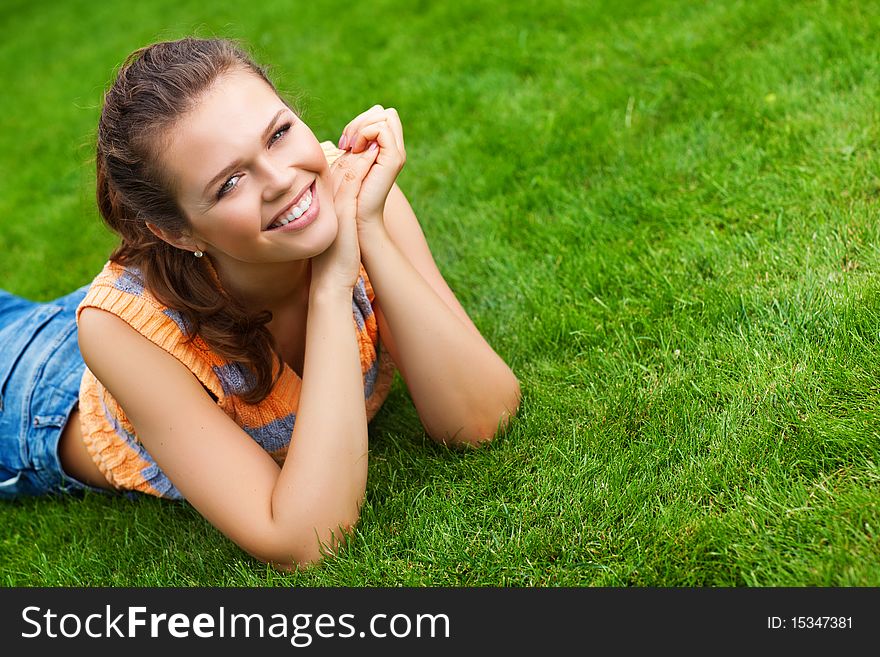 Attractive teenager lying on green lawn smile to the camera. Attractive teenager lying on green lawn smile to the camera