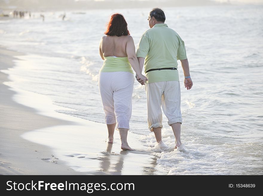 Happy senior mature elderly people couple have romantic time on beach at sunset. Happy senior mature elderly people couple have romantic time on beach at sunset