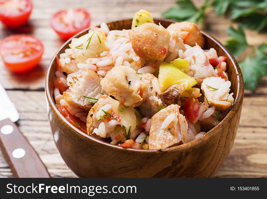 Stewed rice with chicken and vegetables in a wooden bowl,