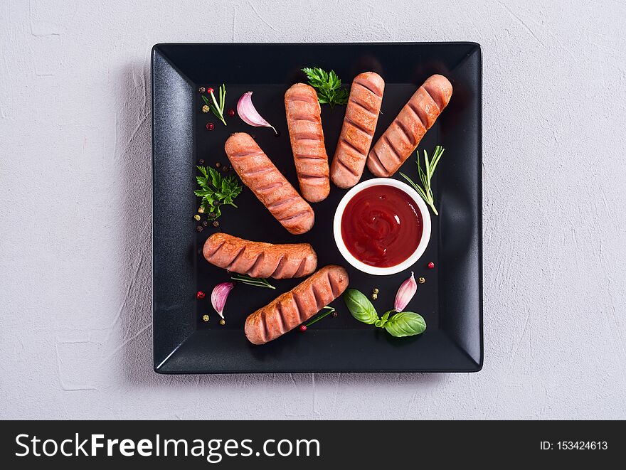 Fried sausages with herbs , spices and ketchup . Food background