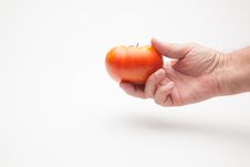 Tomato In Hand On Plain Background Stock Photos