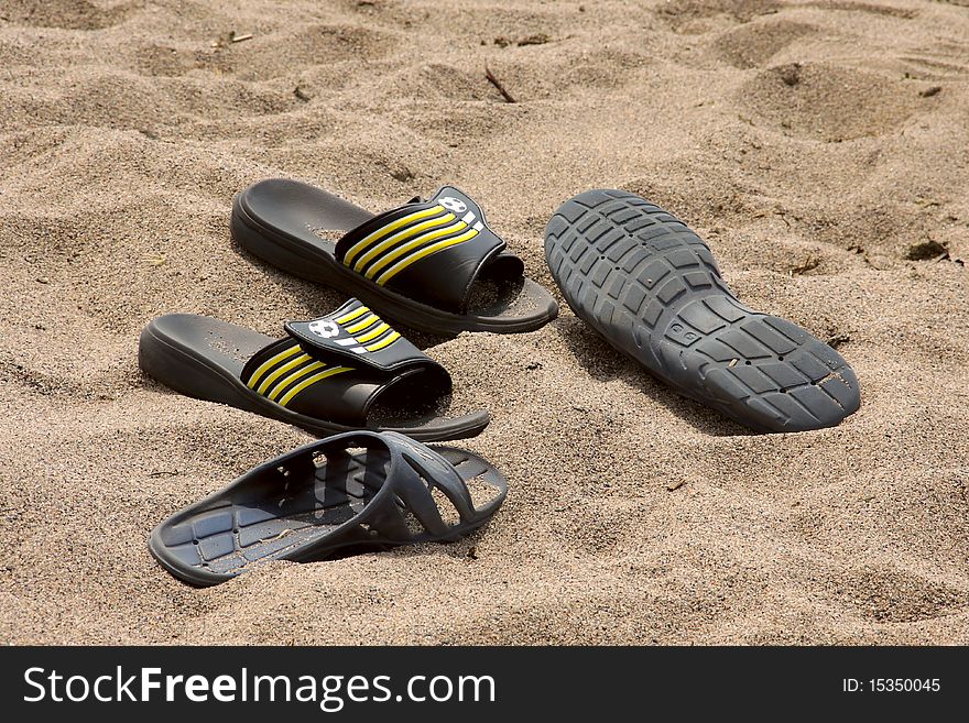 Two pairs slippers on coast, on sand. Two pairs slippers on coast, on sand