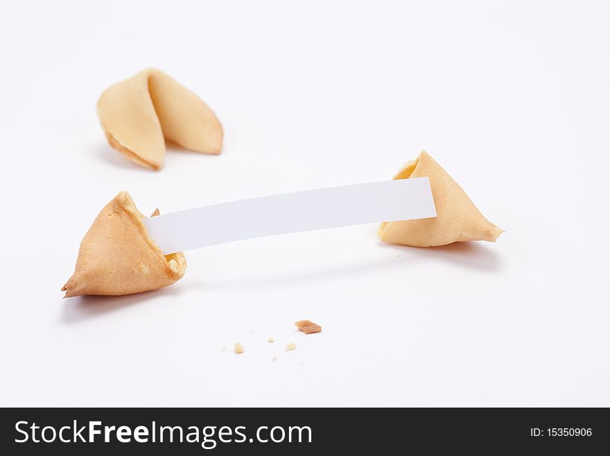 Fortune cookie broken open to reveal extra long fortune on blank paper with another cookie in the background