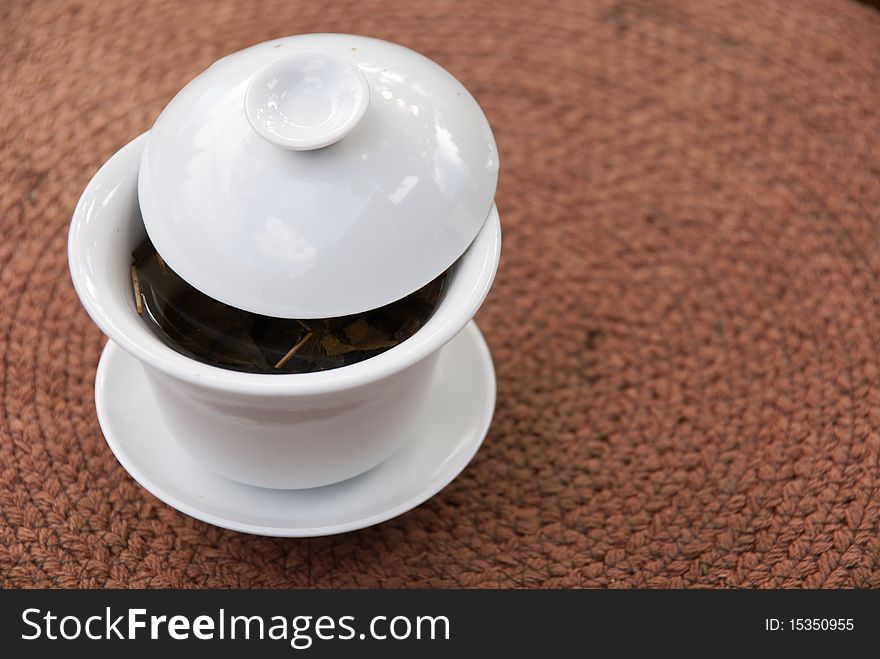 Traditional Chinese white porcelain teacup on a woven brown mat. Traditional Chinese white porcelain teacup on a woven brown mat