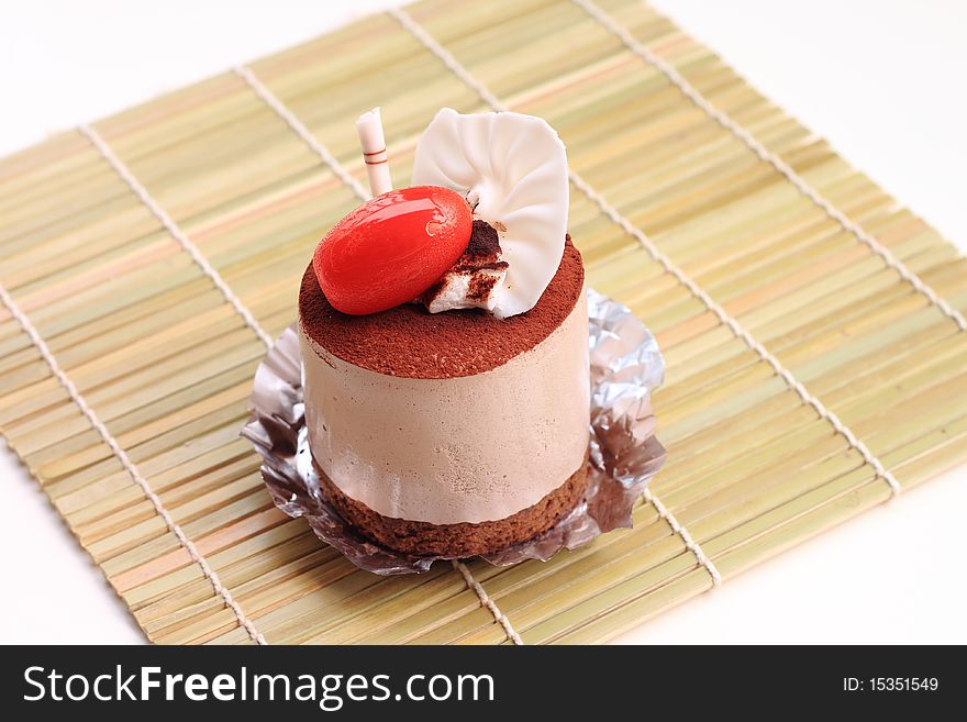 A very delicious Chocolate Mousse Cake with a red Cherry tomato on it.