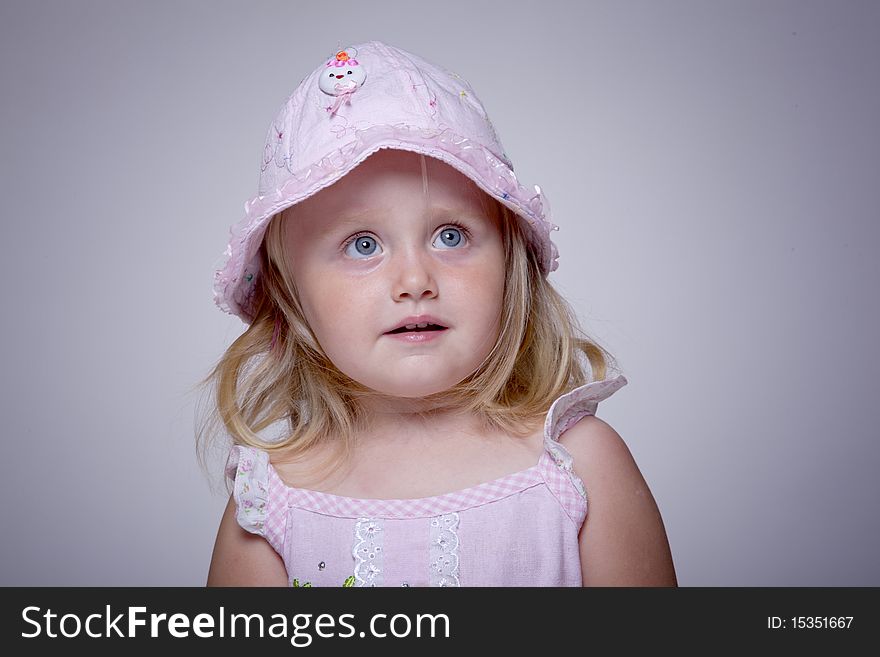Innocent look portrait of a little girl with pink hat