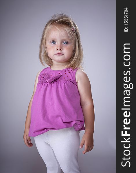 Cute blonde little girl with pink blouse and white pants. Cute blonde little girl with pink blouse and white pants