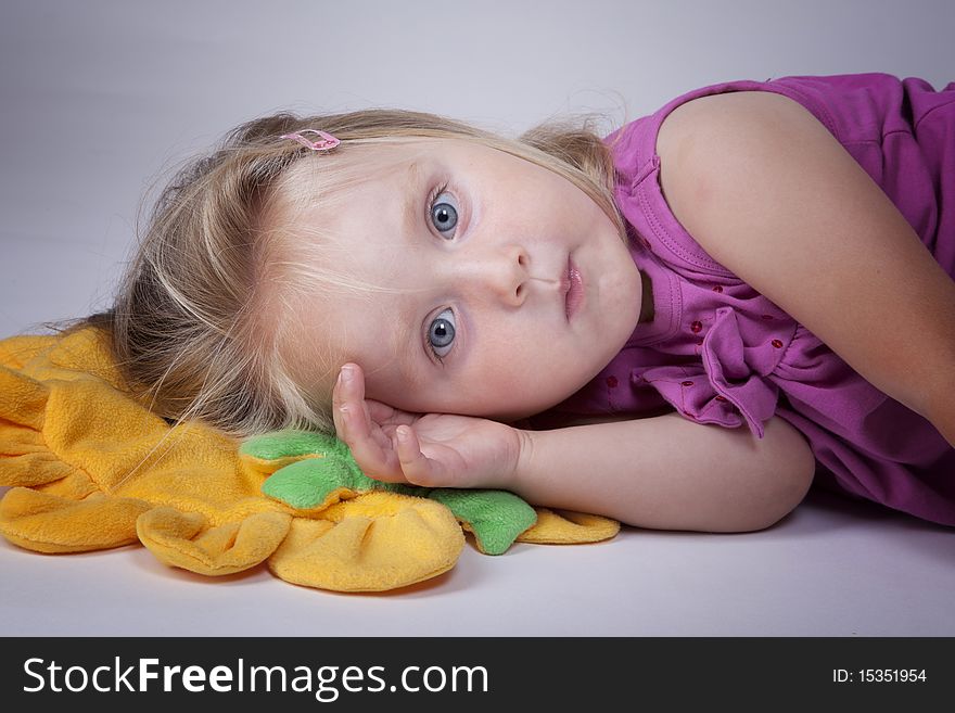 Little girl ready to take a nap on a yellow pillow. Little girl ready to take a nap on a yellow pillow