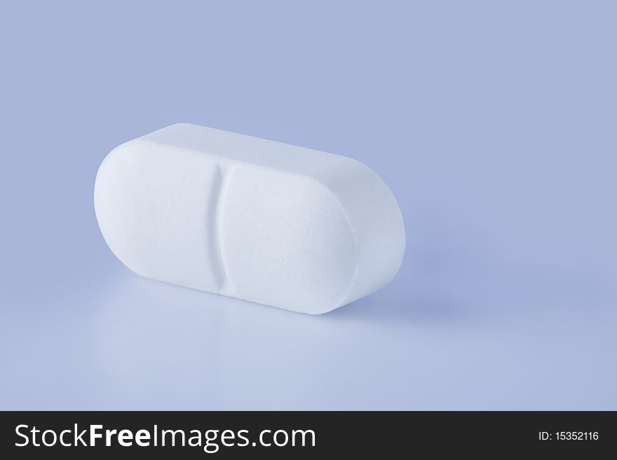 White pill on a table, close up view. White pill on a table, close up view