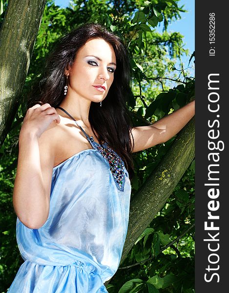 Fashion shoot of a young brunette girl in a light blue dress. The image is taken outdoors, on a nature background with sky trees and water. Fashion shoot of a young brunette girl in a light blue dress. The image is taken outdoors, on a nature background with sky trees and water.