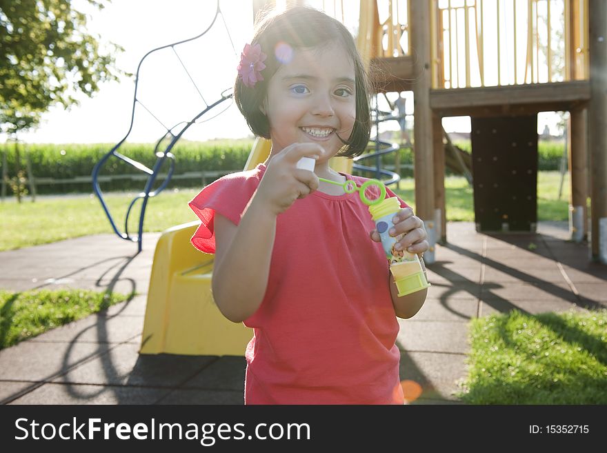 Cute little girl making soap bubbles in a park