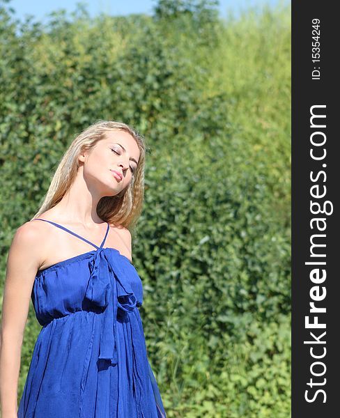 Blond girl in dark blue dress on the green backgrount