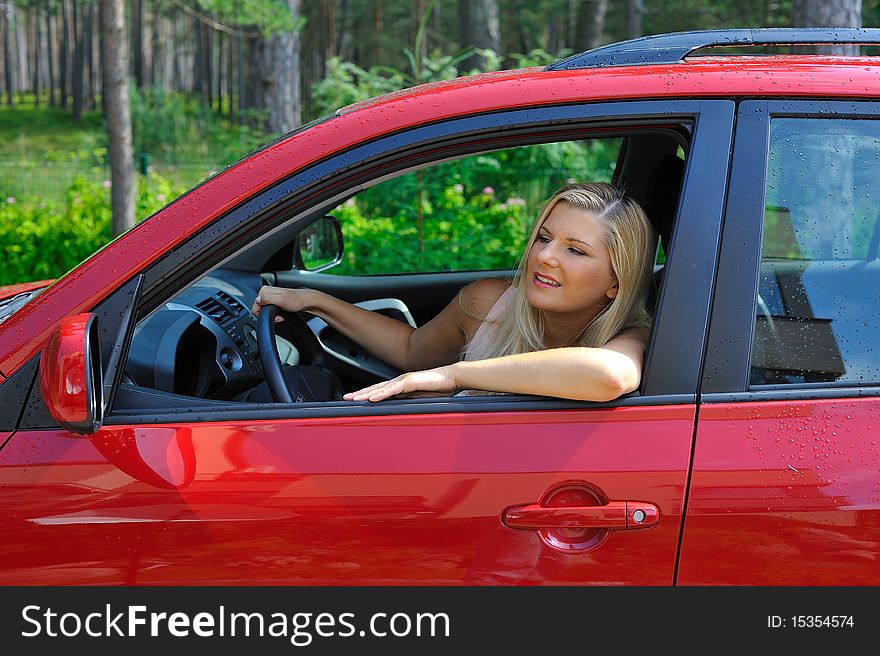 Beautiful woman driver in red shiny car outdoors smiling