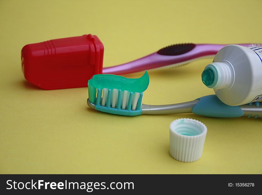 Two tooth brushes on with a travel cap on and one with toothpaste on it tube of tooth paste opened. Two tooth brushes on with a travel cap on and one with toothpaste on it tube of tooth paste opened