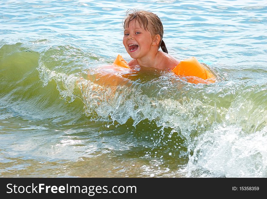 The little girl swims in sea waves
