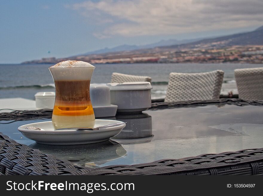 Tasty colorful sweet coffee on the table in a cafe by the ocean in summer