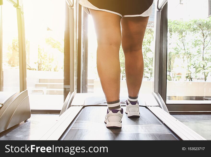 Close up shoes woman running on treadmill. Woman with muscular legs in gym