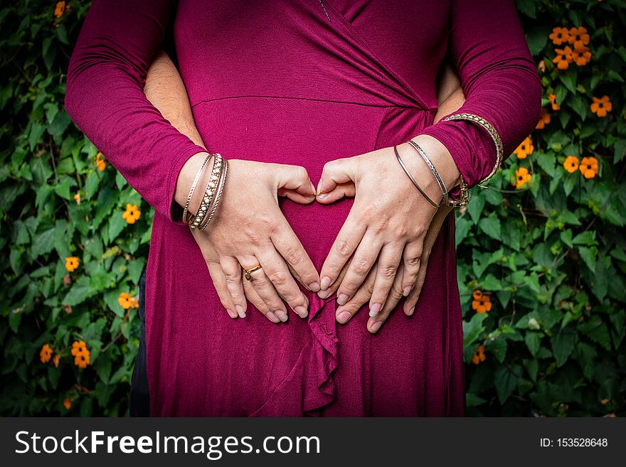 Couple together embracing the pregnancy belly, hands together forming a heart