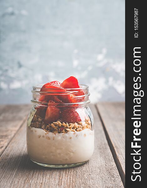Healthy breakfast with yogurt, muesli and red ripe strawberry. Selective focus. Shallocw depth of field.