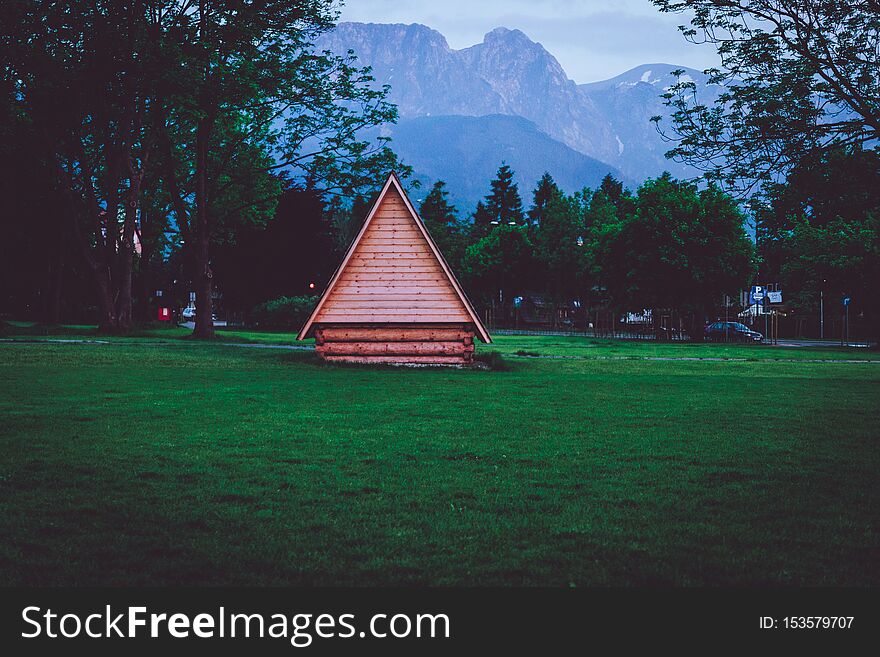 Wooden house standing on a lawn and mountains in the background