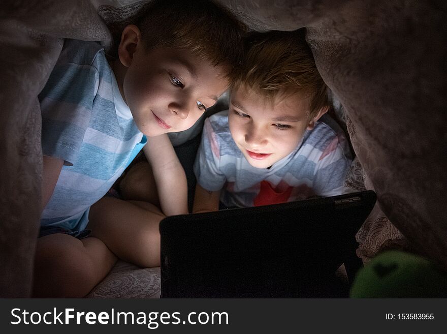 Brothers kids with tablet computer under blanket