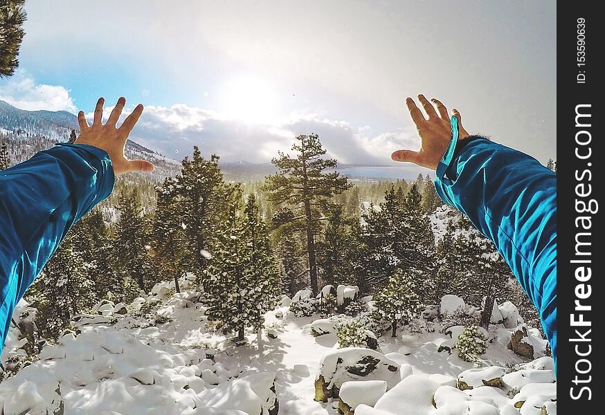 Male hands stretching toward the beautiful snowy forest with South Lake Tahoe in the background