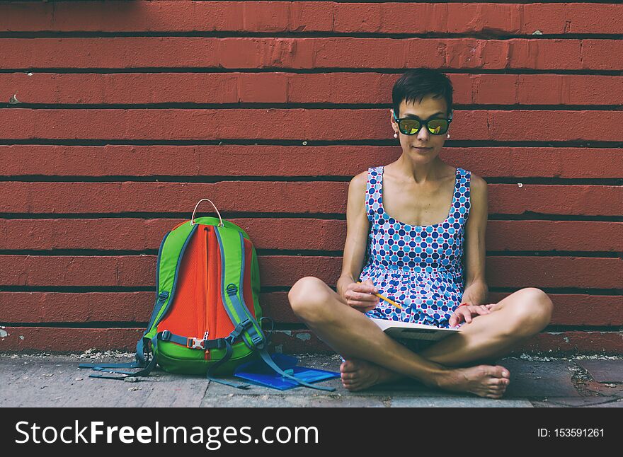 Barefoot Girl Draws Sitting Near A Brick Wall