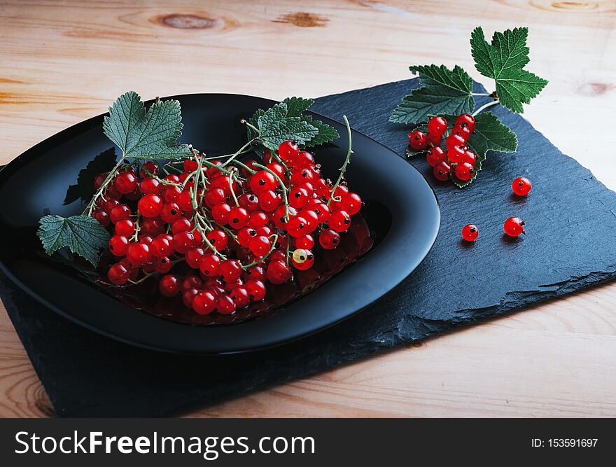 Redcurrants On A Black Plate On A Wooden Table