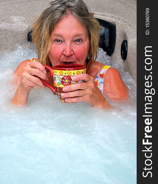 Woman having her morning coffee while relaxing in the hot tub. Woman having her morning coffee while relaxing in the hot tub.