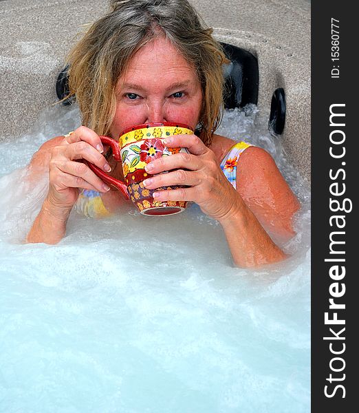 Woman having her morning coffee while relaxing in the hot tub. Woman having her morning coffee while relaxing in the hot tub.