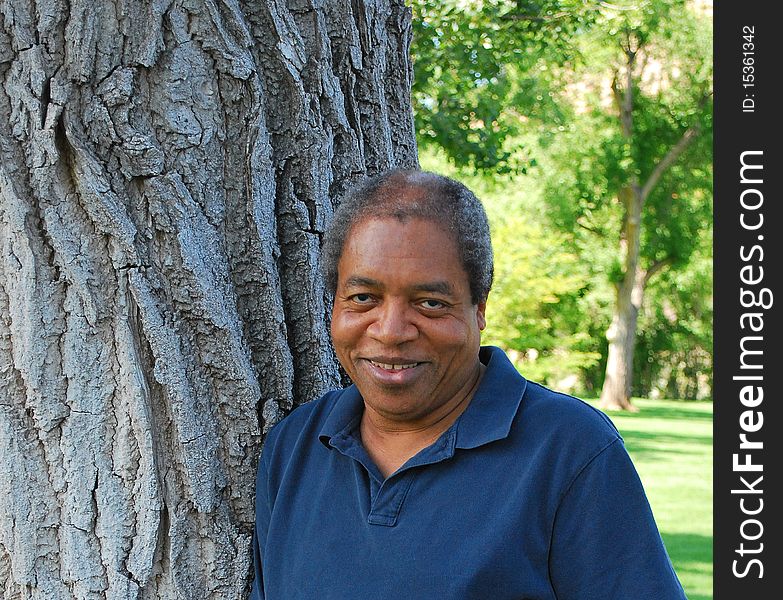 African american man standing by a tree outdoors. African american man standing by a tree outdoors.