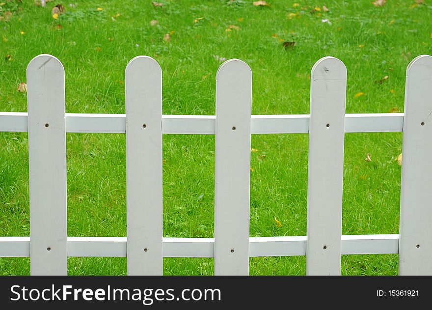 A picket fence with a green lawn as a background