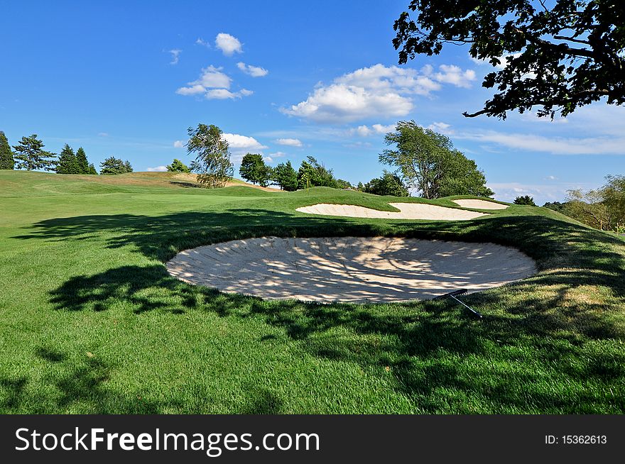 A series of bunkers on a golf course in mid-summer with one in the shade. A series of bunkers on a golf course in mid-summer with one in the shade