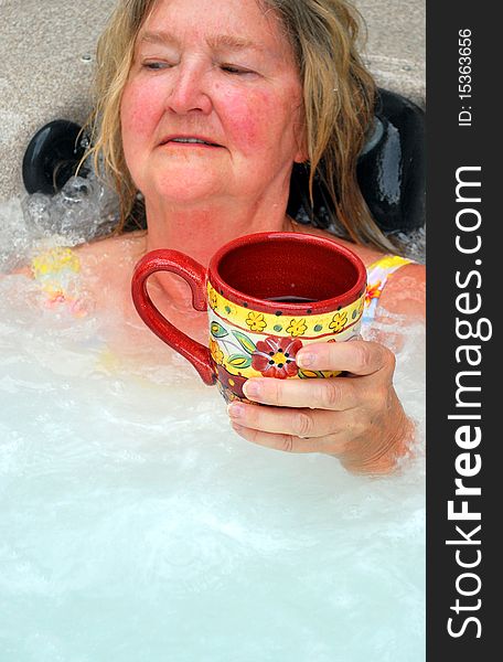 Woman having her morning coffee while relaxing in the hot tub. Woman having her morning coffee while relaxing in the hot tub.